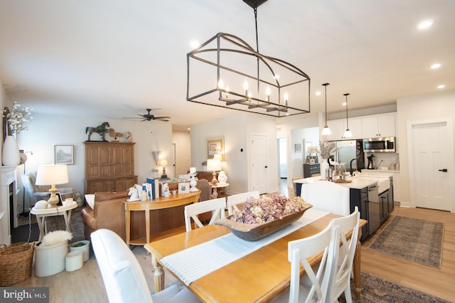 dining room featuring ceiling fan with notable chandelier, light wood finished floors, and recessed lighting