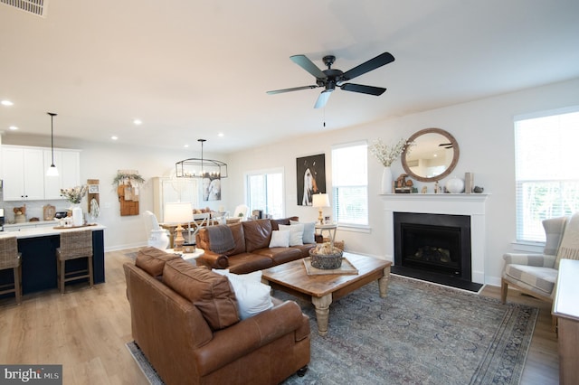 living area featuring recessed lighting, light wood-style flooring, visible vents, and a fireplace with flush hearth