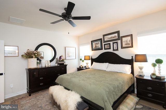 bedroom featuring a ceiling fan, wood finished floors, visible vents, and baseboards