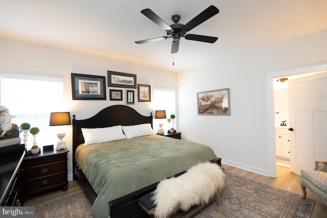 bedroom with ensuite bathroom, ceiling fan, wood finished floors, and baseboards