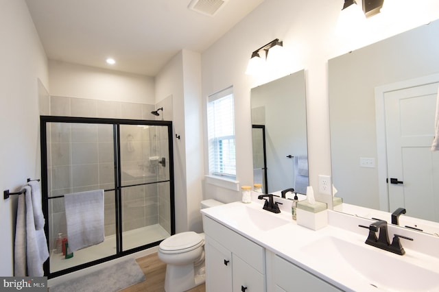 bathroom with a stall shower, visible vents, a sink, and toilet