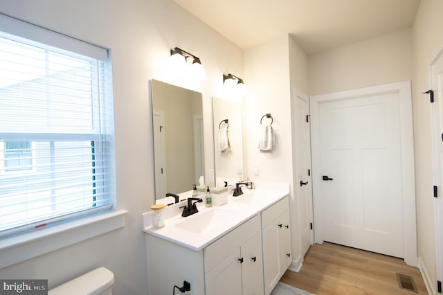 full bath with visible vents, a sink, toilet, and double vanity