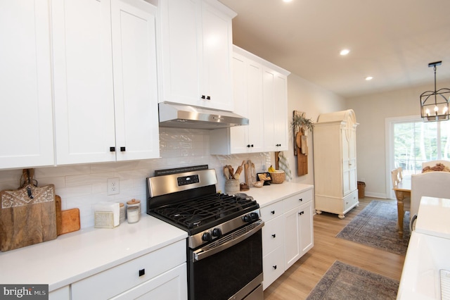 kitchen featuring light wood-style flooring, an inviting chandelier, white cabinets, stainless steel gas range, and under cabinet range hood