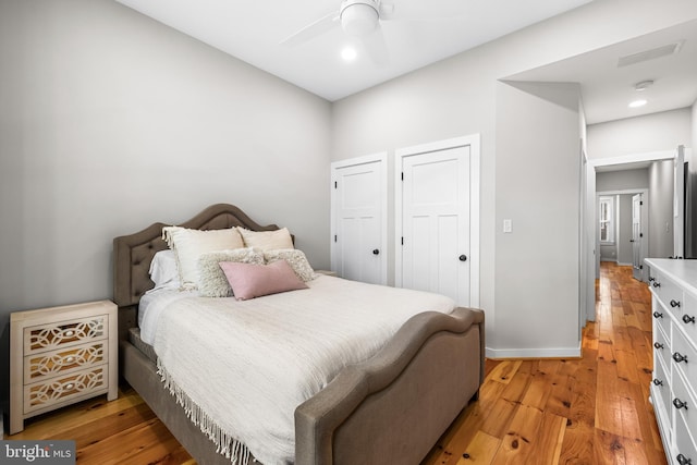 bedroom with multiple closets, ceiling fan, and light wood-type flooring