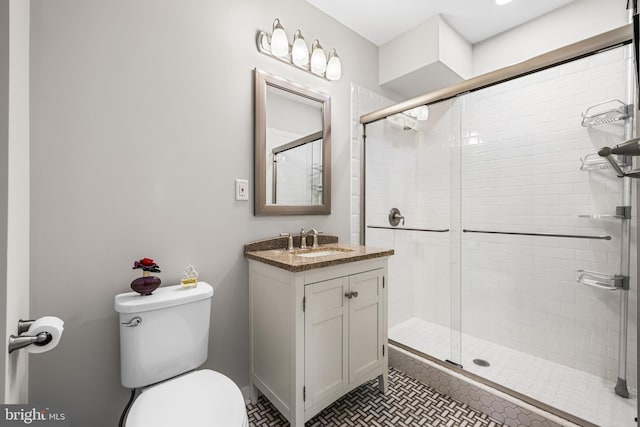 bathroom with tile patterned flooring, walk in shower, vanity, and toilet