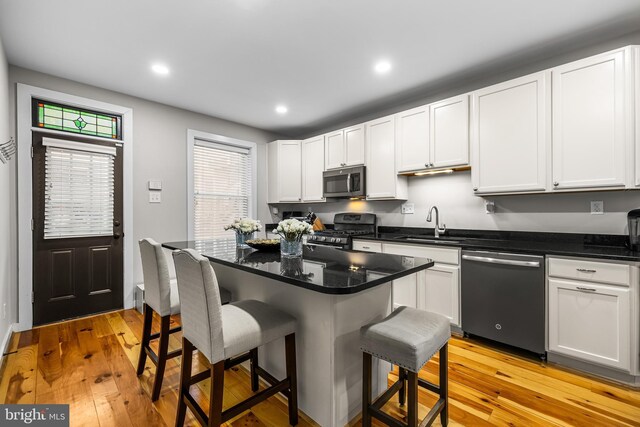 kitchen featuring stainless steel appliances, white cabinetry, a breakfast bar, and sink