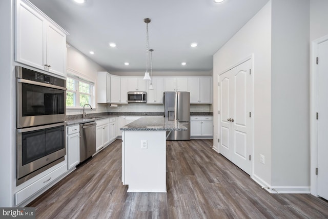 kitchen featuring stainless steel appliances, white cabinetry, a kitchen island, and decorative light fixtures