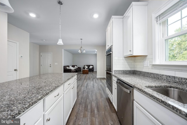 kitchen featuring pendant lighting, appliances with stainless steel finishes, white cabinetry, dark hardwood / wood-style floors, and stone countertops