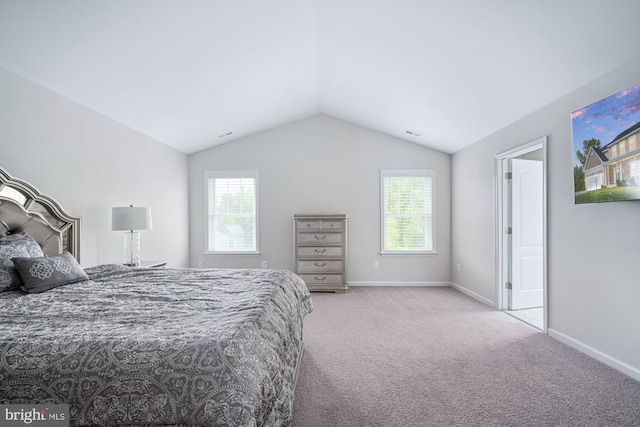 bedroom featuring multiple windows, lofted ceiling, and light colored carpet