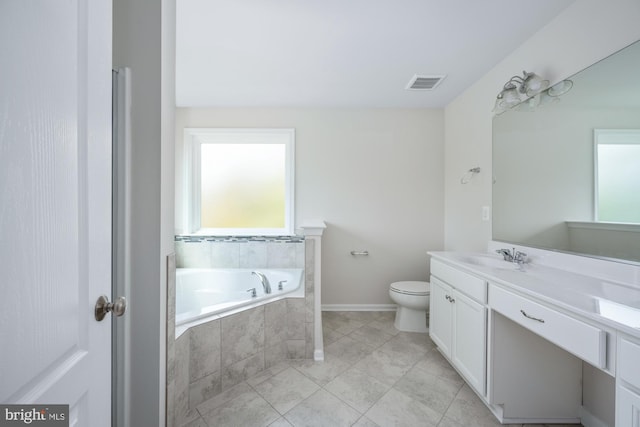 bathroom with vanity, tiled bath, and toilet