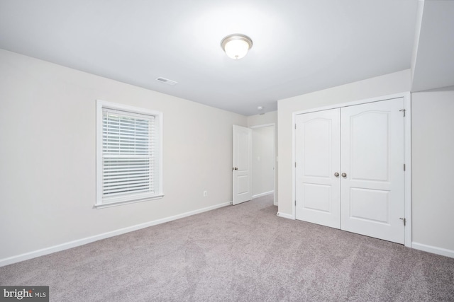 unfurnished bedroom with light carpet and a closet