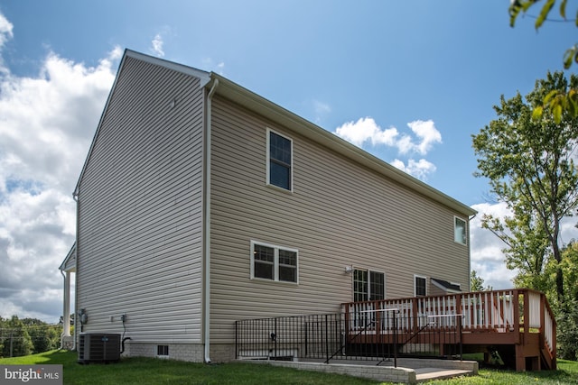 rear view of property featuring central AC, a deck, and a lawn