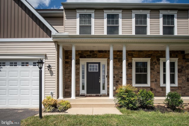 view of exterior entry with a garage and a porch