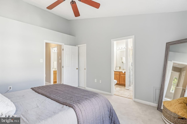 bedroom with ceiling fan, vaulted ceiling, light carpet, and ensuite bath