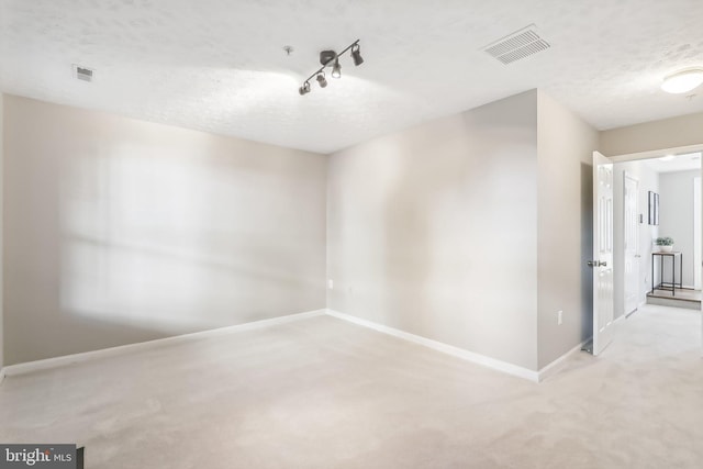 unfurnished room featuring a textured ceiling and light colored carpet