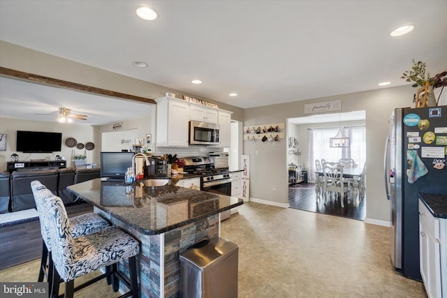 kitchen featuring sink, a breakfast bar area, white cabinetry, appliances with stainless steel finishes, and dark stone counters