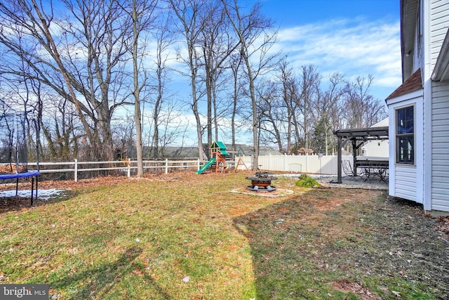 view of yard featuring a playground, a pergola, a trampoline, and an outdoor fire pit