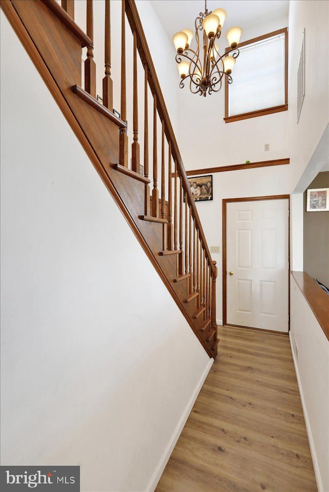 foyer featuring hardwood / wood-style flooring, an inviting chandelier, and a towering ceiling