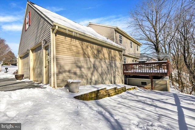 view of snowy exterior featuring a garage and a wooden deck