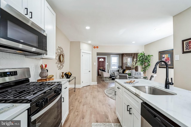 kitchen with sink, white cabinets, light stone countertops, and appliances with stainless steel finishes