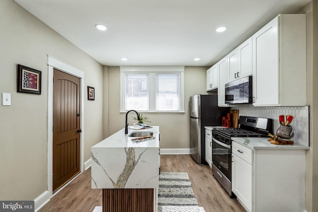 kitchen with light stone countertops, decorative backsplash, sink, white cabinets, and stainless steel appliances