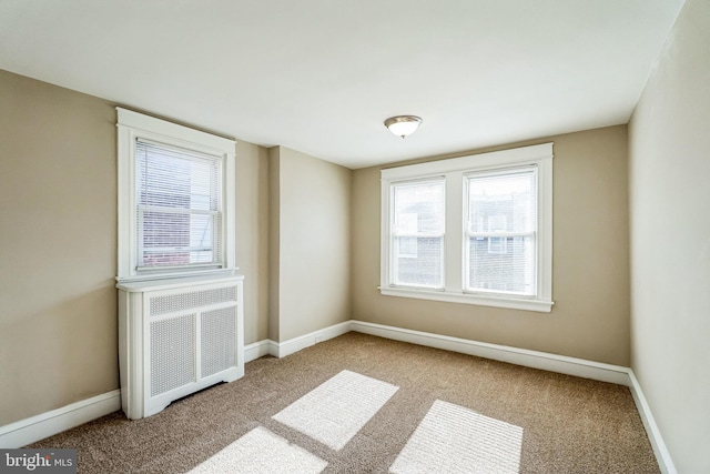 spare room featuring carpet flooring and radiator