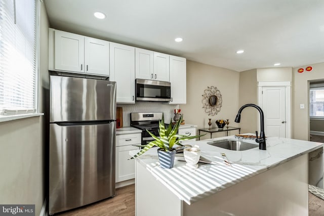 kitchen featuring sink, a kitchen island with sink, light stone countertops, and stainless steel appliances