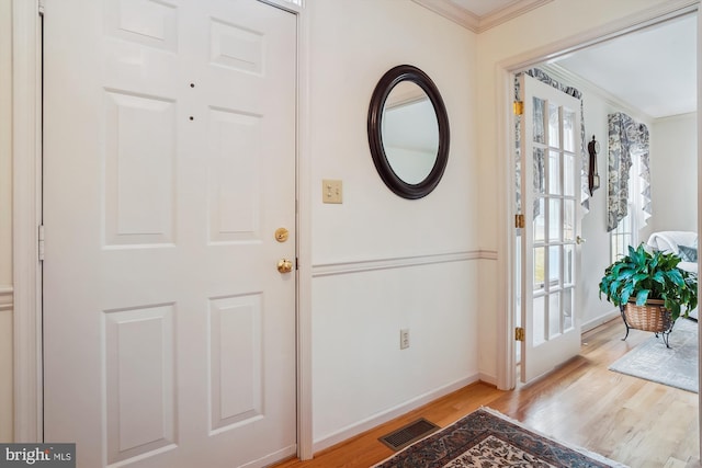 foyer featuring light hardwood / wood-style flooring, crown molding, and a wealth of natural light