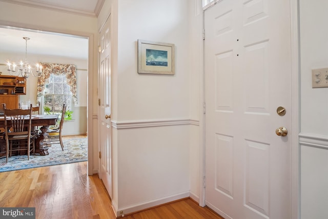 foyer entrance featuring a notable chandelier, crown molding, and light hardwood / wood-style flooring