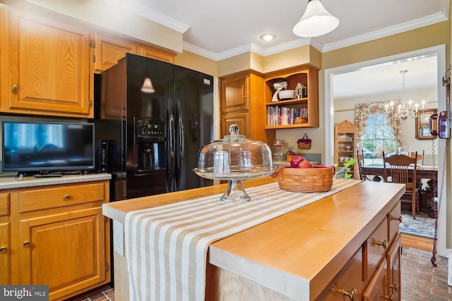 kitchen featuring ornamental molding, decorative light fixtures, black fridge with ice dispenser, and a kitchen island