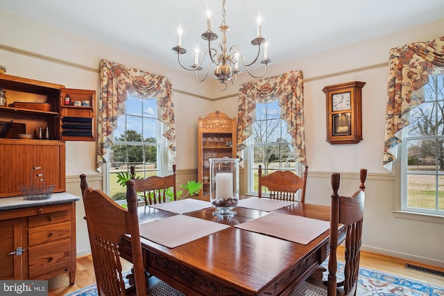 dining area with light hardwood / wood-style flooring and a notable chandelier