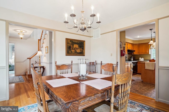 dining room with an inviting chandelier, ornamental molding, and wood-type flooring