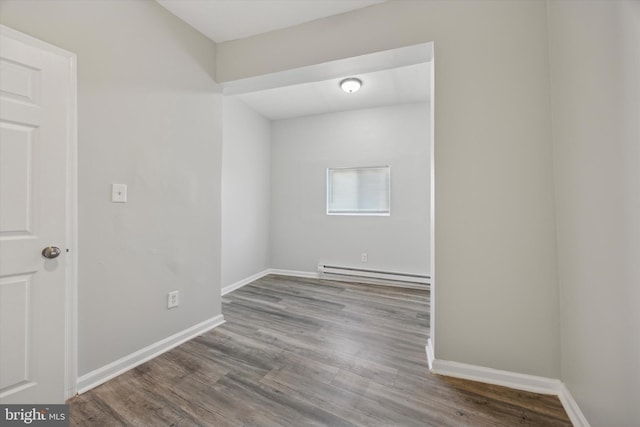 unfurnished room featuring hardwood / wood-style flooring and a baseboard radiator