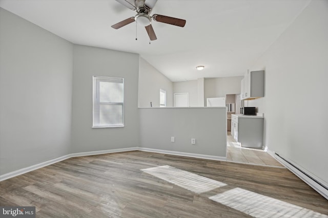 spare room with baseboard heating, ceiling fan, lofted ceiling, and light wood-type flooring