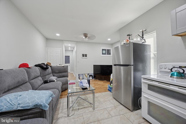 kitchen featuring white cabinets, stainless steel fridge, range with two ovens, light tile patterned floors, and ceiling fan