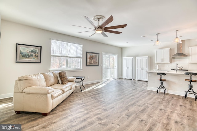 living room with ceiling fan, sink, and light hardwood / wood-style flooring