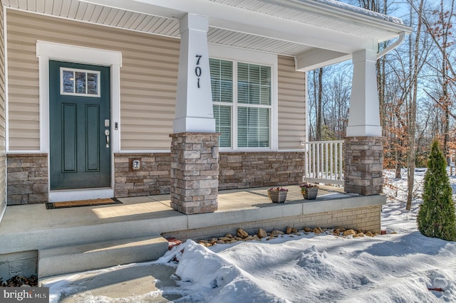 snow covered property entrance with a porch