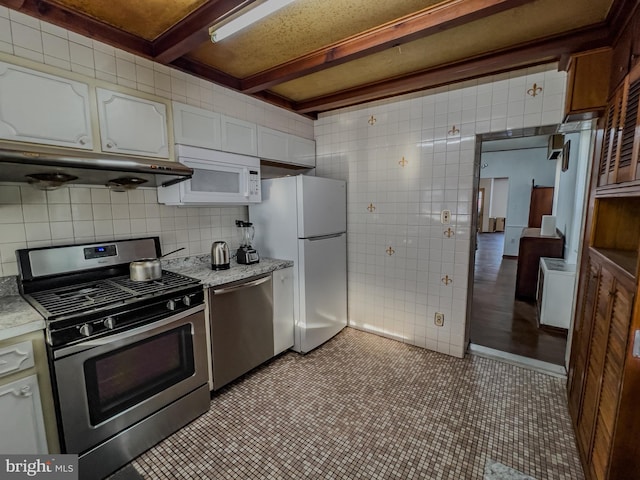 kitchen featuring white cabinetry, tasteful backsplash, tile walls, appliances with stainless steel finishes, and beam ceiling