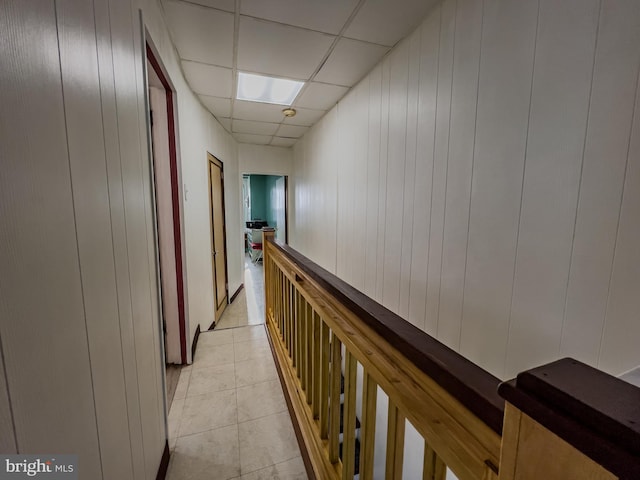 hallway featuring light tile patterned flooring and a drop ceiling