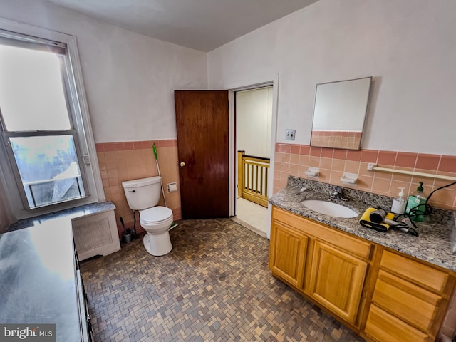 bathroom featuring tile walls, radiator, vanity, and toilet