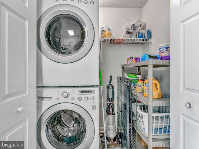 washroom with a textured ceiling and stacked washing maching and dryer