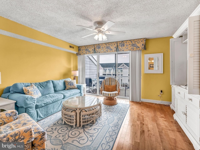 living room with ceiling fan, light hardwood / wood-style flooring, and a textured ceiling