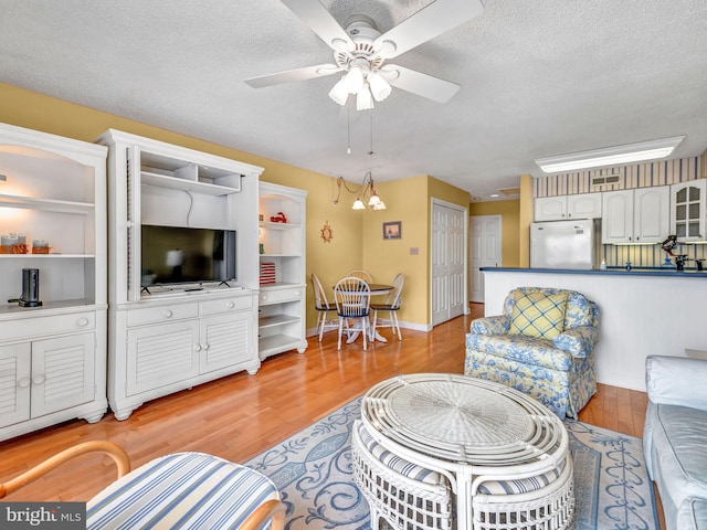 living room with ceiling fan, a textured ceiling, and light hardwood / wood-style floors