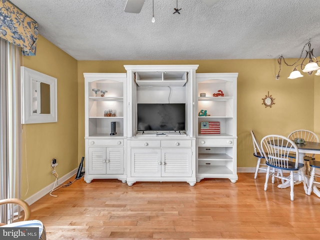 living room featuring ceiling fan, a textured ceiling, and light hardwood / wood-style floors