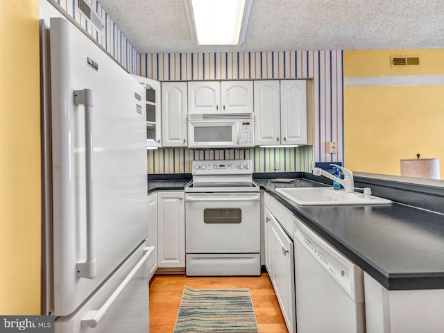 kitchen with white cabinetry, sink, a textured ceiling, and white appliances