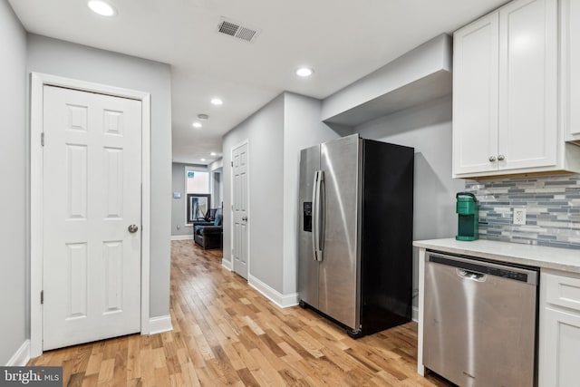 kitchen featuring appliances with stainless steel finishes, tasteful backsplash, white cabinetry, and light hardwood / wood-style floors