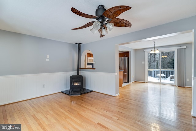 unfurnished living room with light wood-type flooring, a wood stove, and ceiling fan