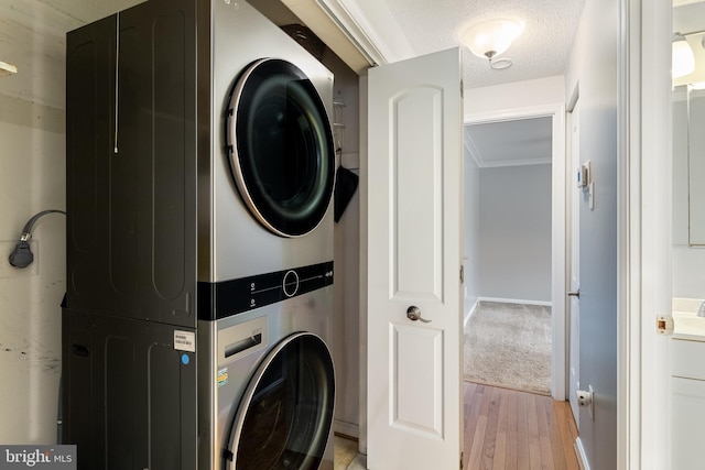 washroom featuring light colored carpet, stacked washer / dryer, and a textured ceiling