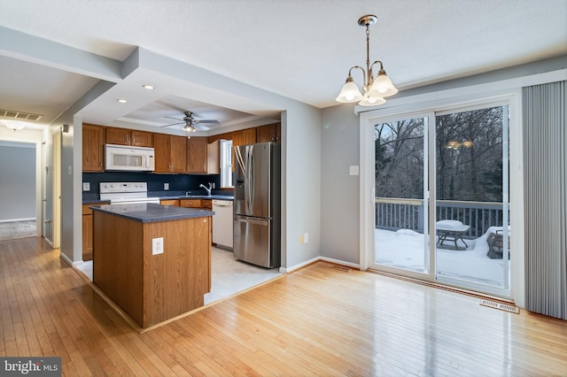 kitchen featuring a center island, white appliances, light hardwood / wood-style floors, tasteful backsplash, and pendant lighting