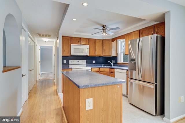 kitchen with ceiling fan, sink, white appliances, a kitchen island, and decorative backsplash